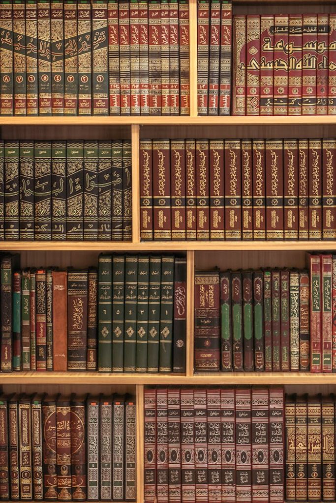 pexels-photo-31679265 A collection of Islamic books neatly arranged on wooden shelves showcasing rich cultural heritage.